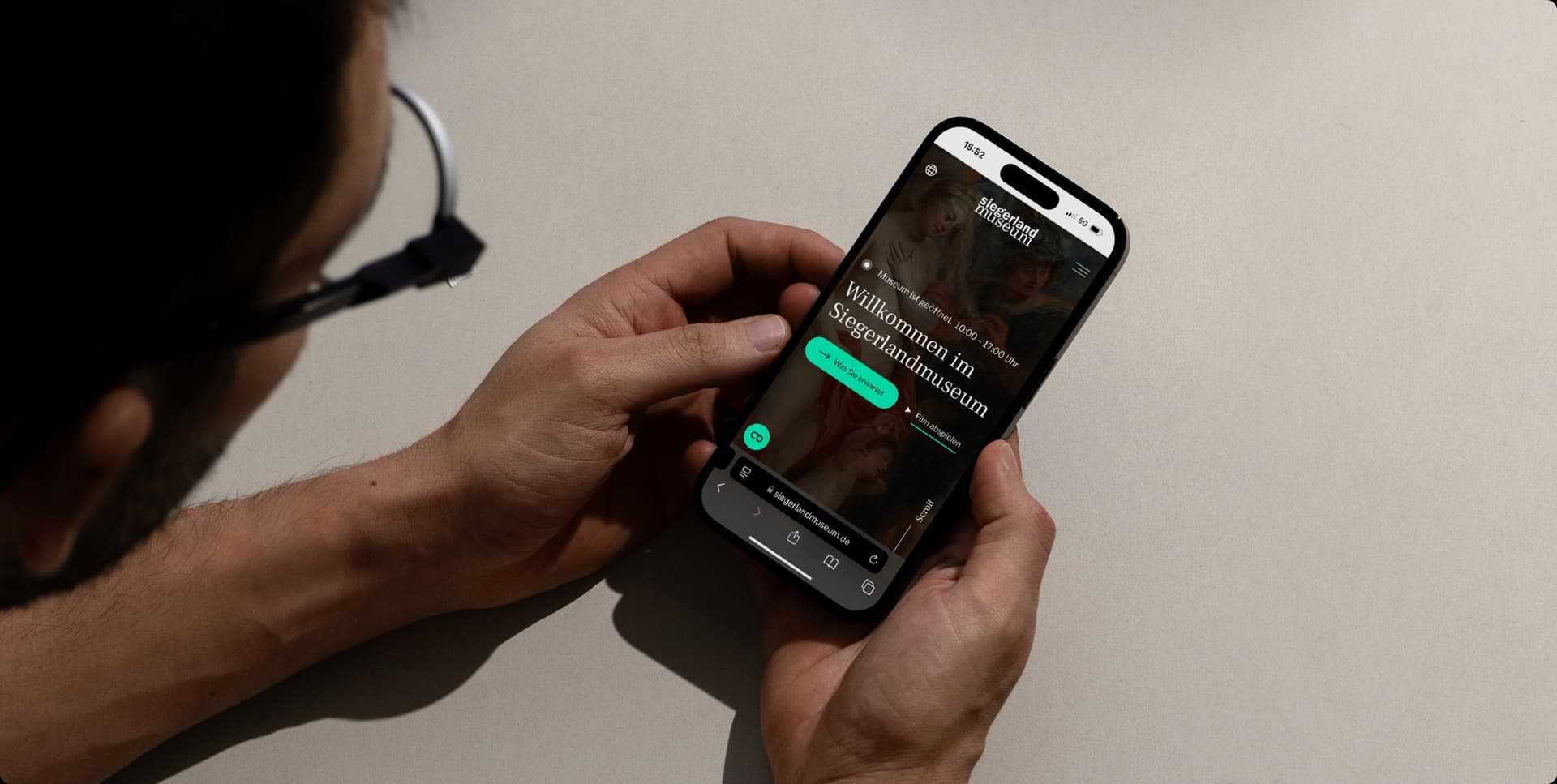 Person betrachtet Smartphone mit geöffneter Website des Sigerlandmuseums.