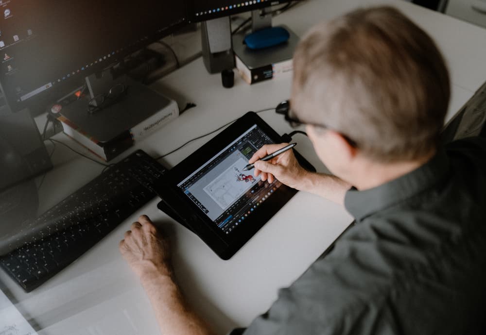 Ein Mann zeichnet bei reaze auf einem iPad eine digitale Skizze.