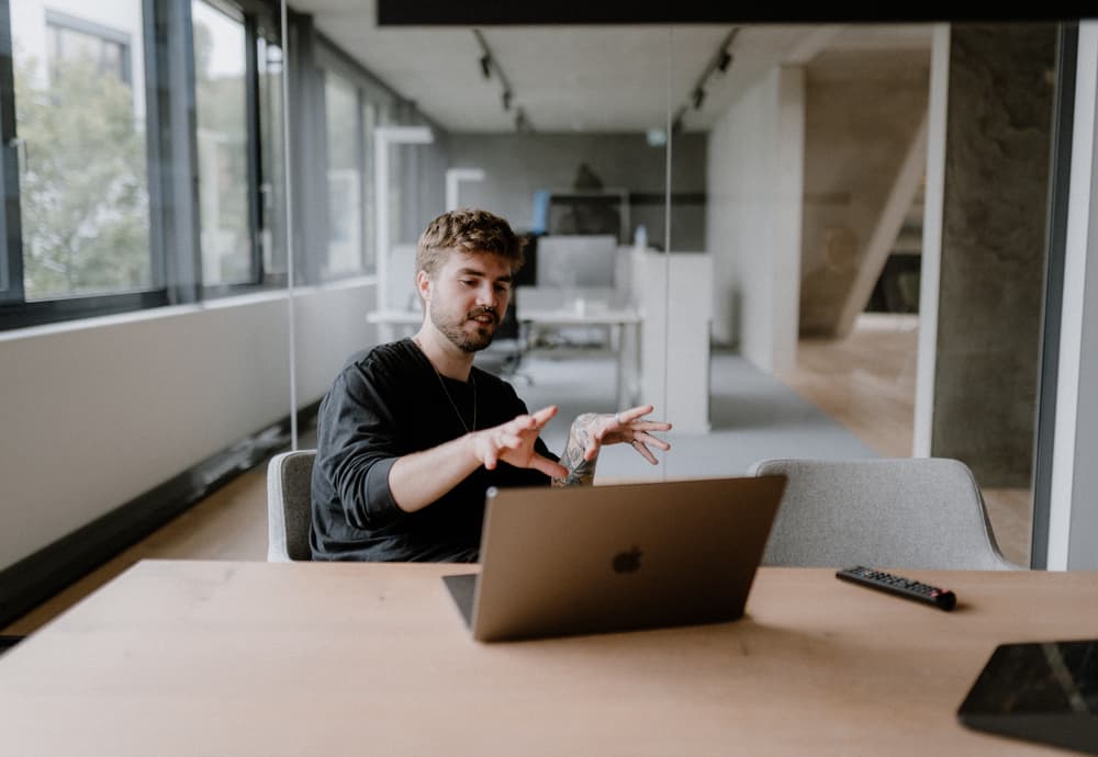 Ein Mitarbeiter von reaze sitzt vor einem Laptop und gestikuliert.